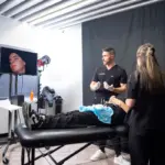 Dr James Olding is presenting an aesthetics treatment during Interface Expo. The face of a patient is broadcast live on TV.